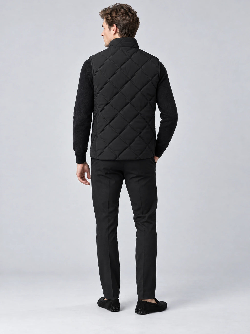 Rear studio view of a model wearing a Black Quilted Puffer Vest with diamond quilting and a stand collar.