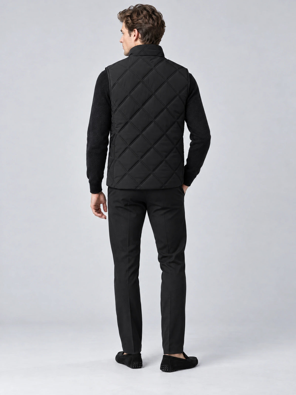 Rear studio view of a model wearing a Black Quilted Puffer Vest with diamond quilting and a stand collar.