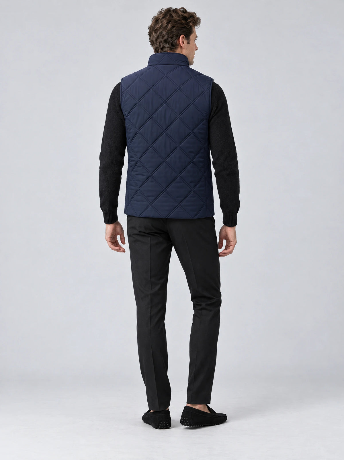 Rear studio view of a model wearing a Navy Quilted Puffer Vest with diamond quilting and a stand collar.