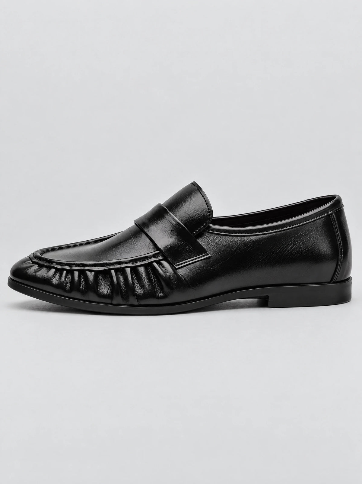 Side view of a Black ruched leather loafer with a stitched moc toe and slip-on strap.