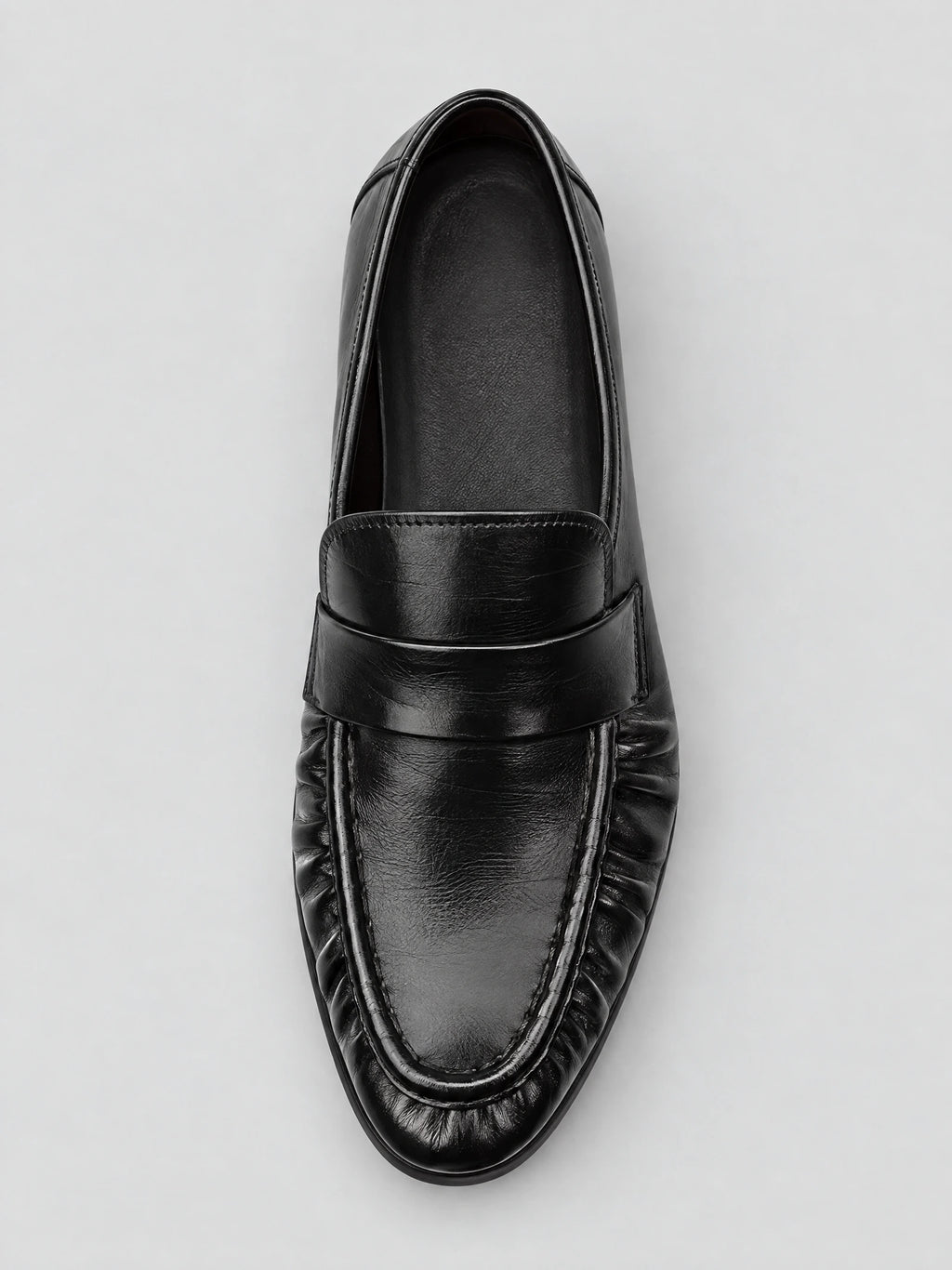 Top-down view of a Black ruched leather loafer with a stitched apron toe and slip-on vamp.