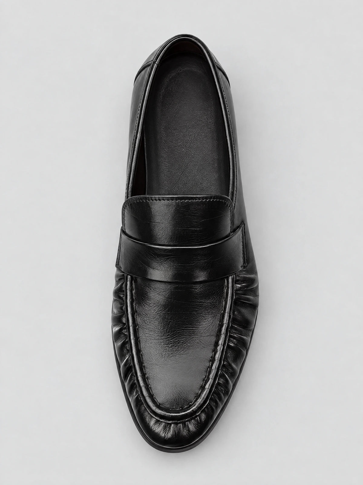 Top-down view of a Black ruched leather loafer with a stitched apron toe and slip-on vamp.