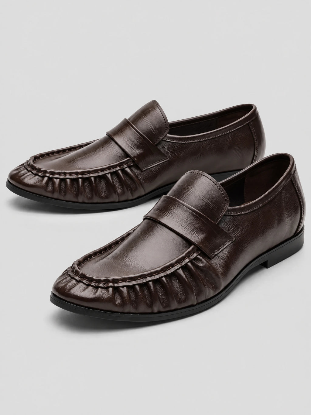 Brown ruched leather loafers with penny straps and stitched moc toes, shown as a pair on a studio background.
