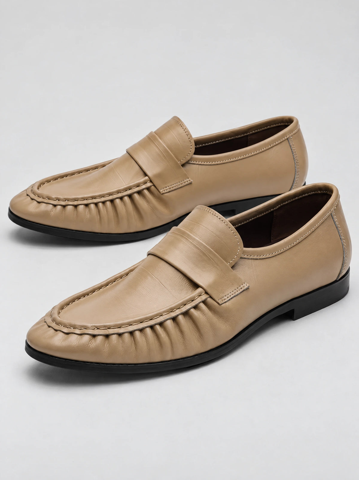 Pair of Khaki ruched leather loafers with stitched moc toes and slip-on straps, shown in a studio product view.