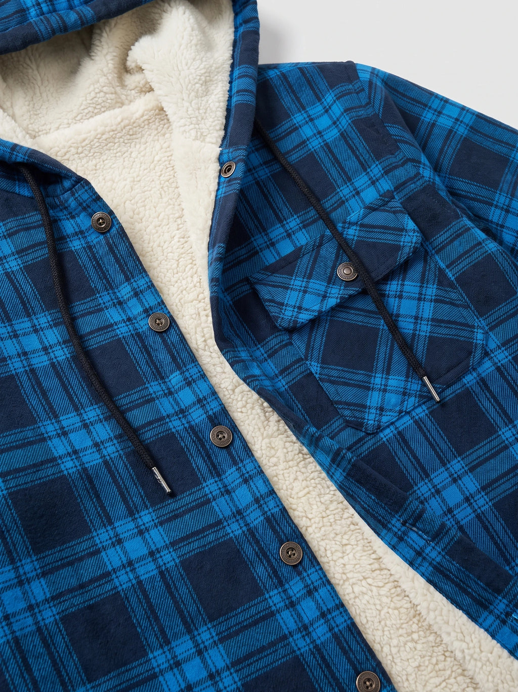 Close-up of the Blue Sherpa Lined Jacket showing its soft interior lining, plaid fabric, snap buttons, hood drawstrings, and chest pocket.