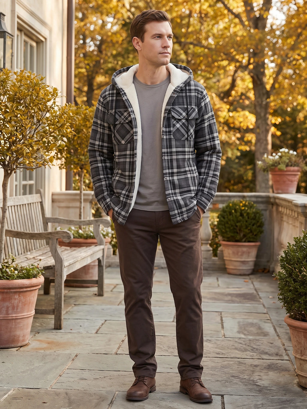 Man wearing a Gray Sherpa Lined Jacket with a hood and chest pockets on a patio lined with potted plants.