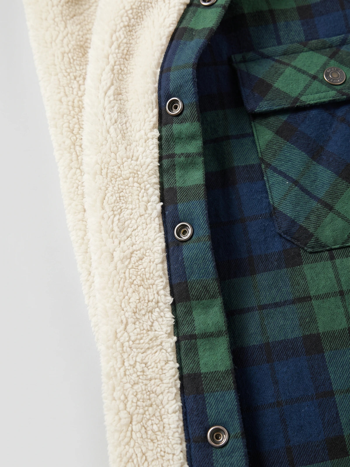 Close-up of the Green Sherpa Lined Jacket showing the soft sherpa interior, plaid outer fabric, snap buttons, and chest pocket.