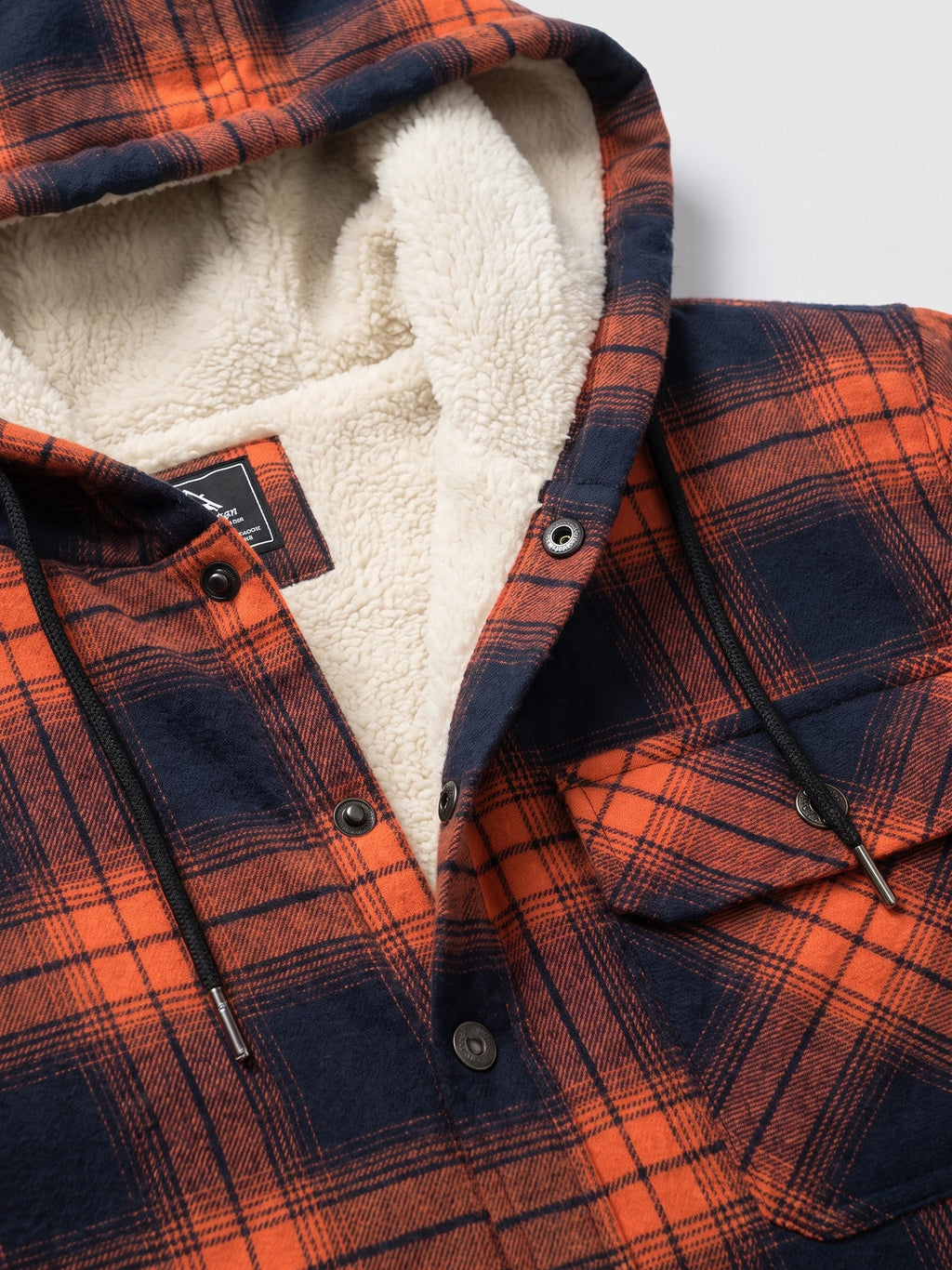 Close-up of the Orange Sherpa Lined Jacket showing the hood’s soft sherpa interior, snap-button placket, drawstrings, and plaid fabric.