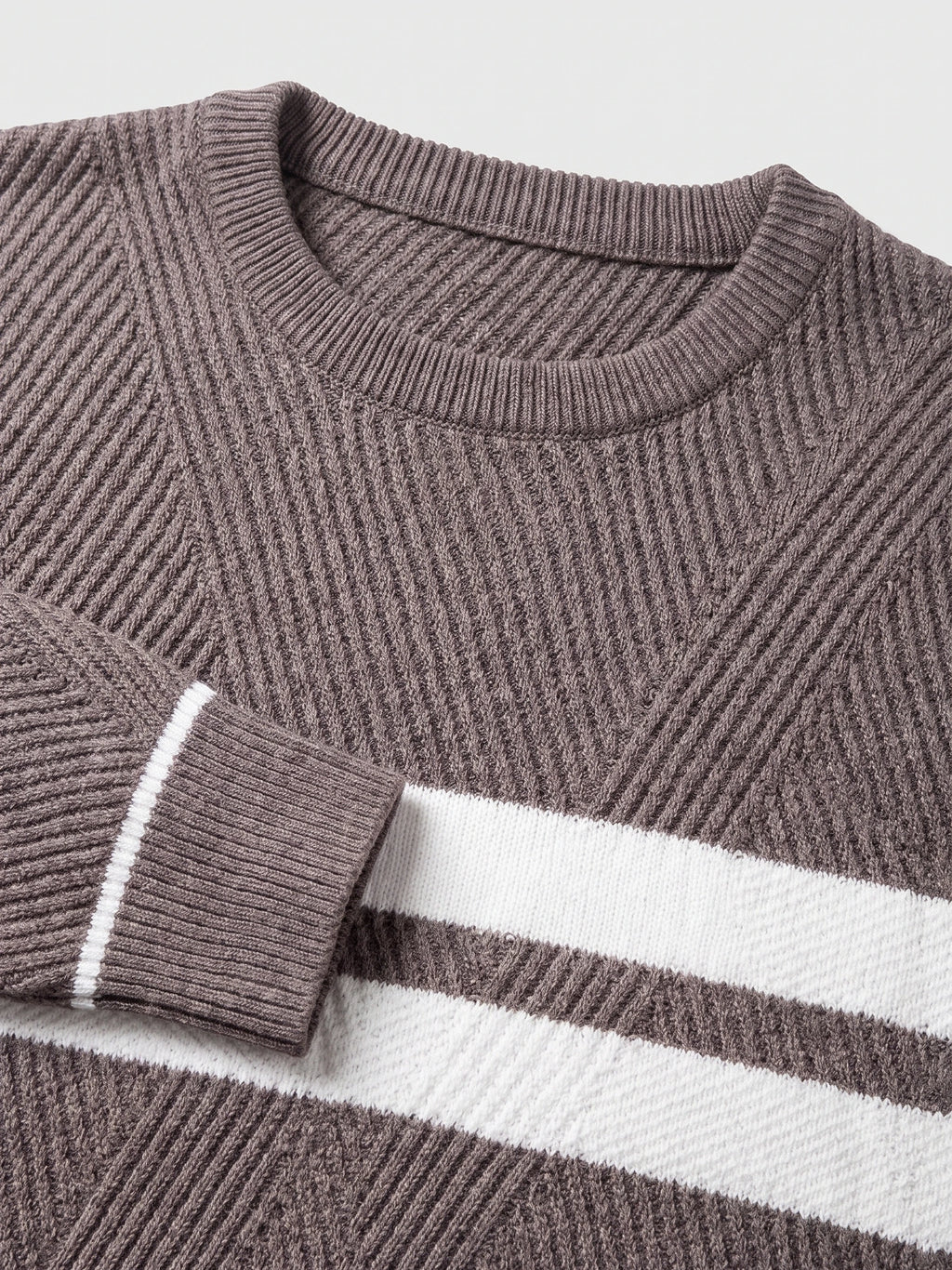 Brown slim sweater detail showing the ribbed crew neckline, textured knit, and striped patchwork panel.
