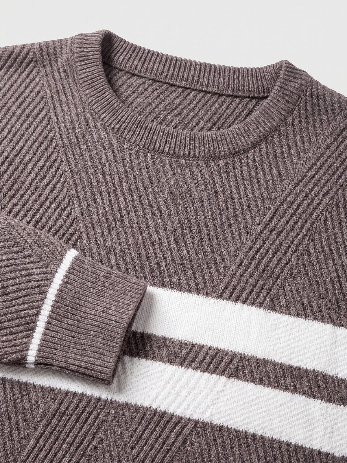 Brown slim sweater detail showing the ribbed crew neckline, textured knit, and striped patchwork panel.