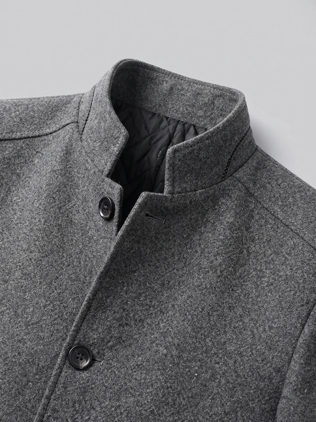 Close-up of the Gray wool overcoat’s stand collar, quilted inner lining, and button-front closure.