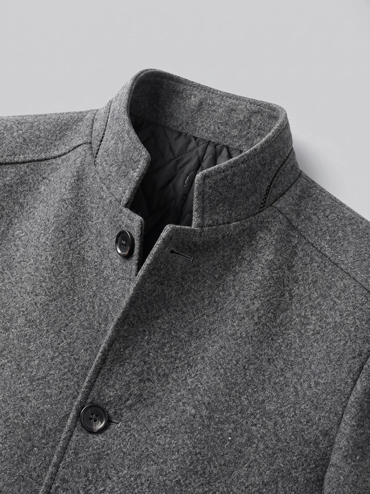 Close-up of the Gray wool overcoat’s stand collar, quilted inner lining, and button-front closure.