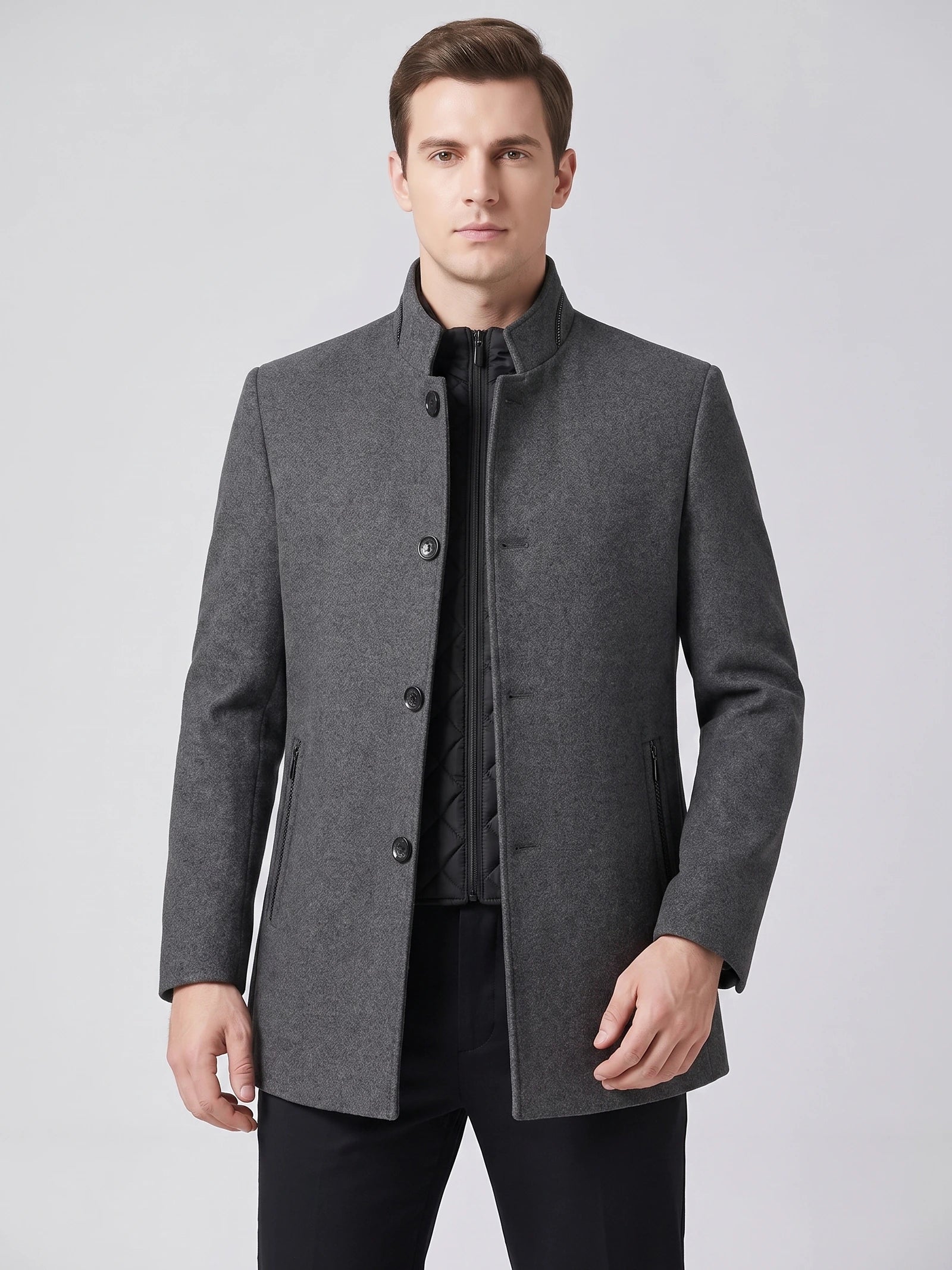 Front studio view of a model wearing a Gray wool overcoat with a stand collar, button closure, zip pockets, and quilted inner layer.