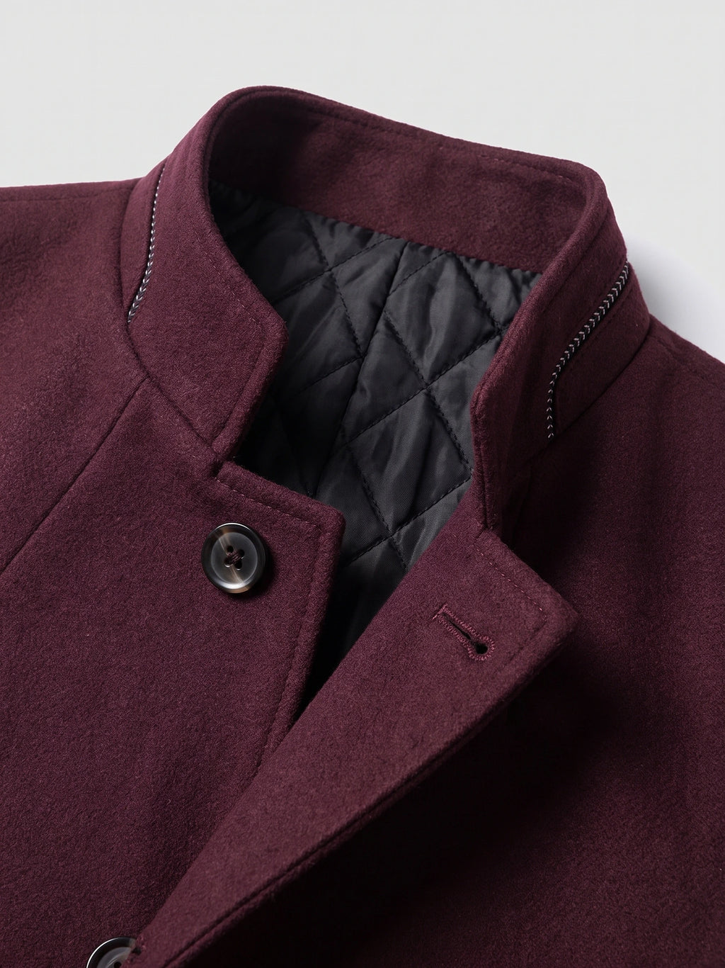 Close-up of the Wine wool overcoat’s stand collar, quilted lining, and buttoned front.