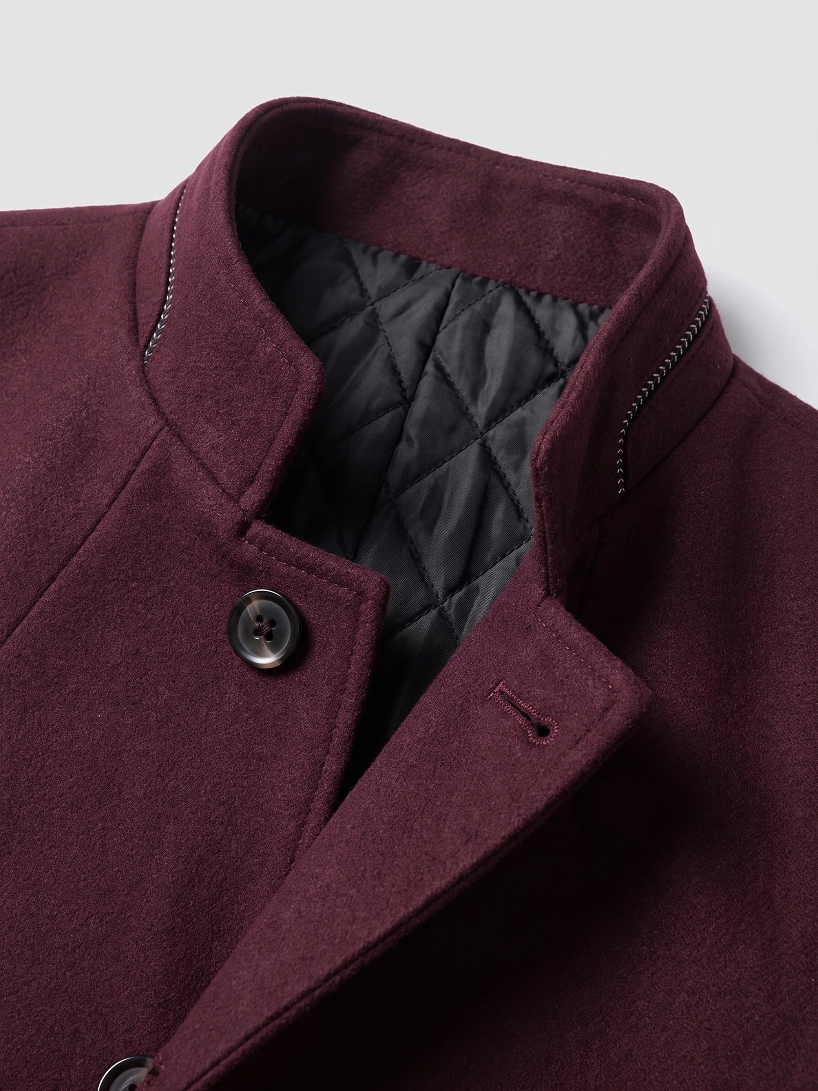Close-up of the Wine wool overcoat’s stand collar, quilted lining, and buttoned front.