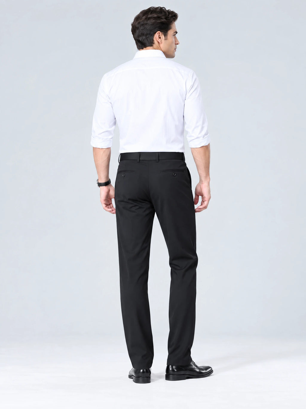 Rear studio view of a model wearing Black men's straight-leg pants with buttoned back welt pockets.