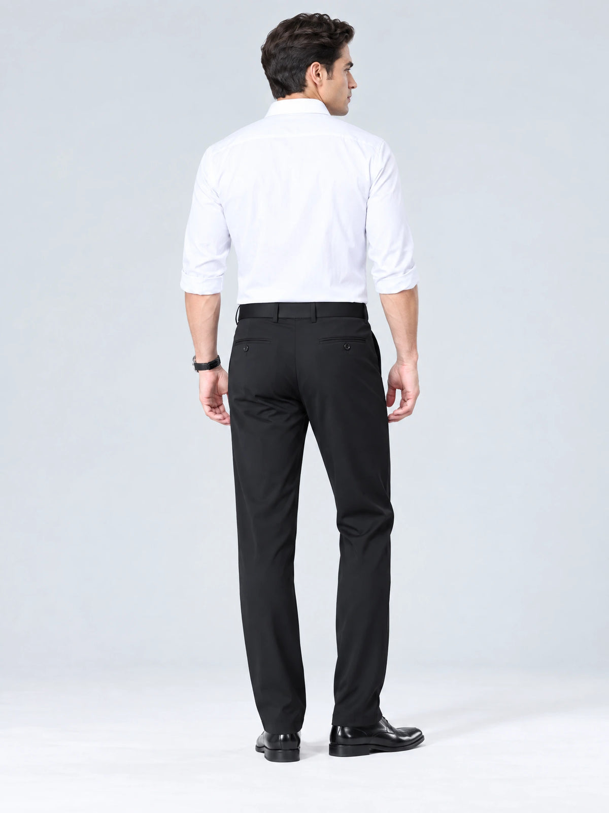 Rear studio view of a model wearing Black men's straight-leg pants with buttoned back welt pockets.
