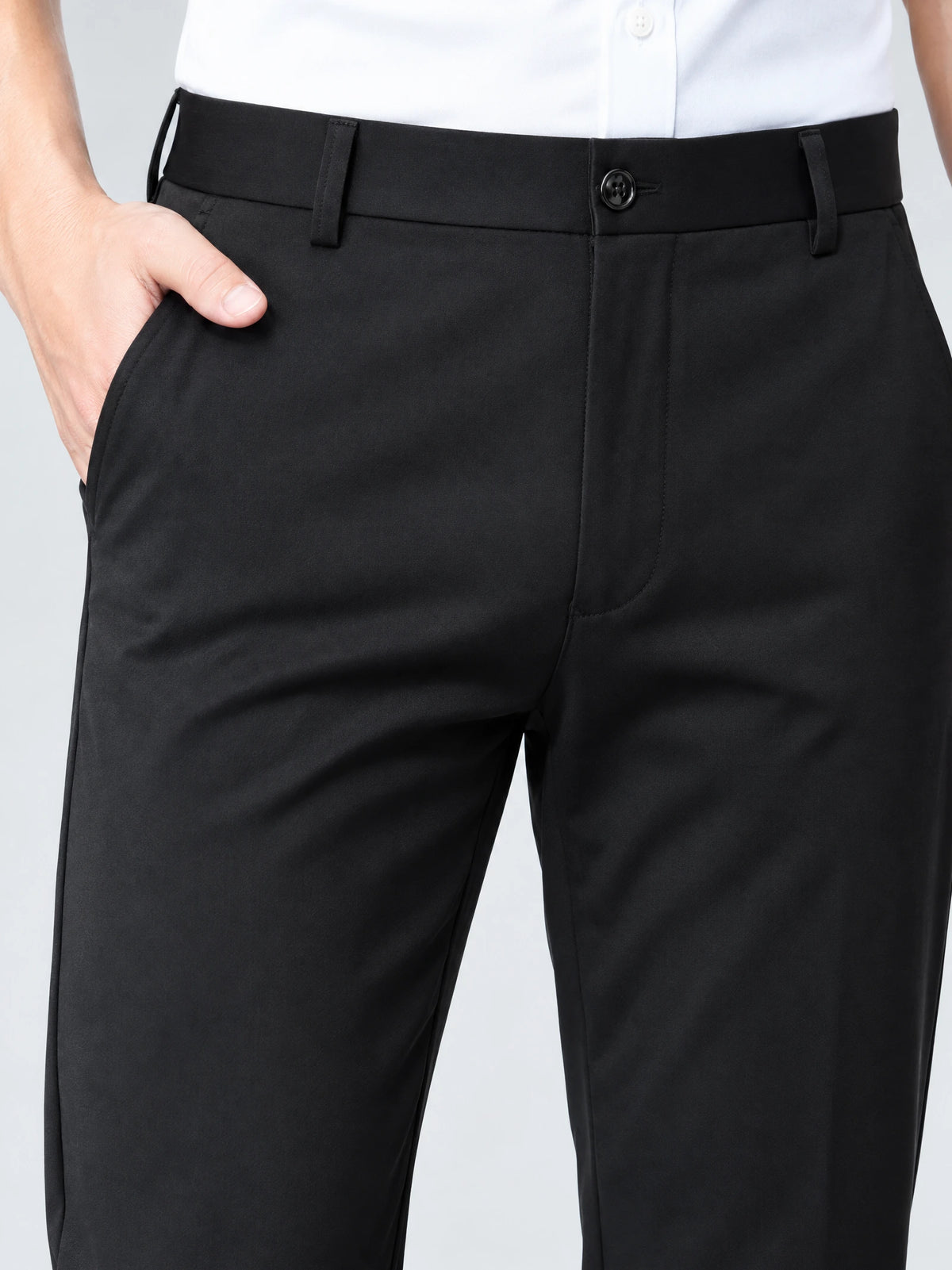 Close-up of Black men's pants showing the buttoned waistband, belt loops, fly, and side pocket.