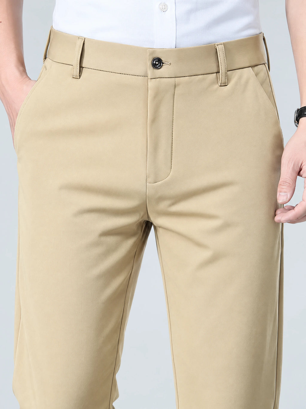 Close-up of Khaki men’s pants showing the button waistband, belt loops, zip fly, and side pockets.