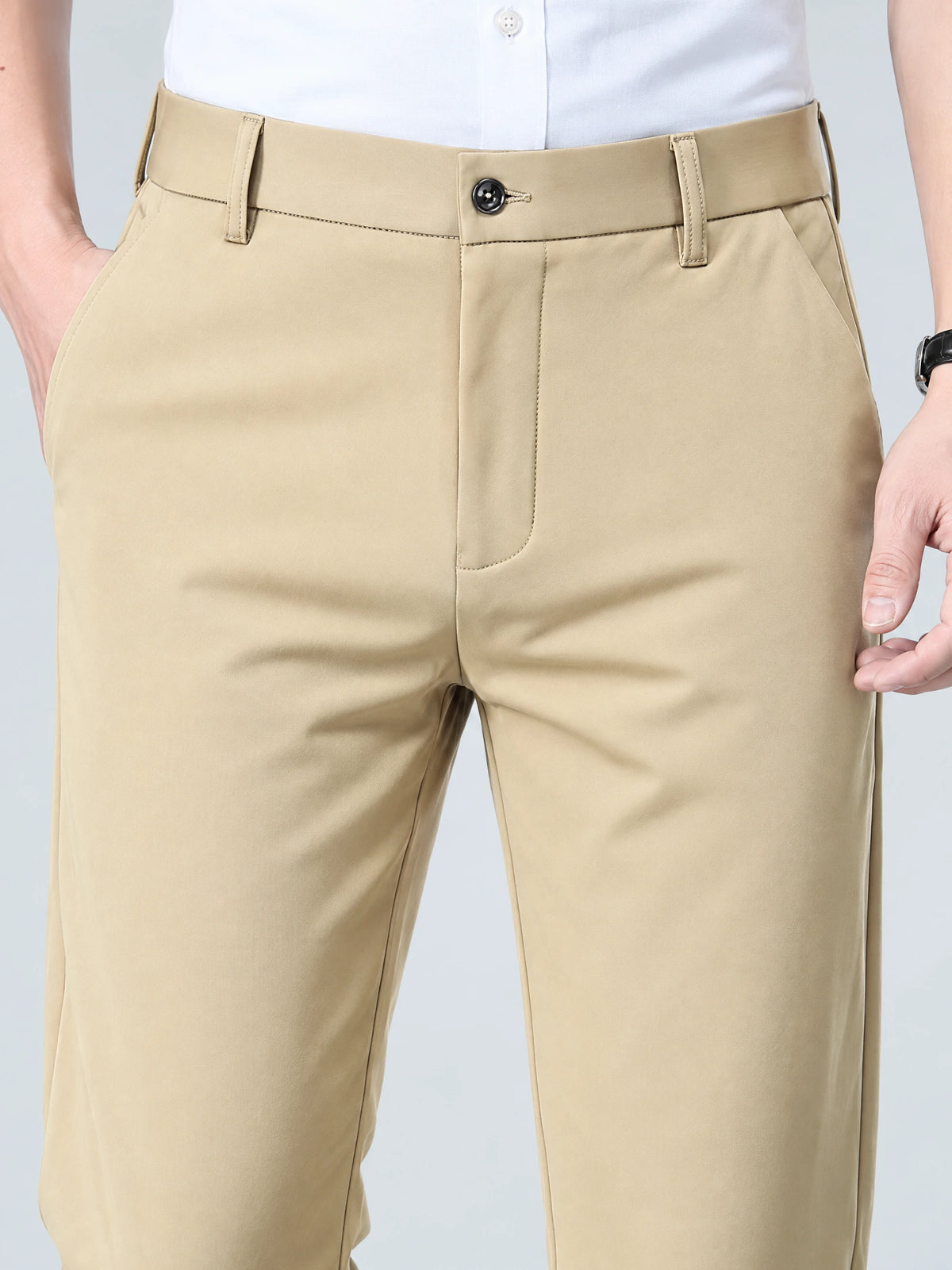 Close-up of Khaki men’s pants showing the button waistband, belt loops, zip fly, and side pockets.