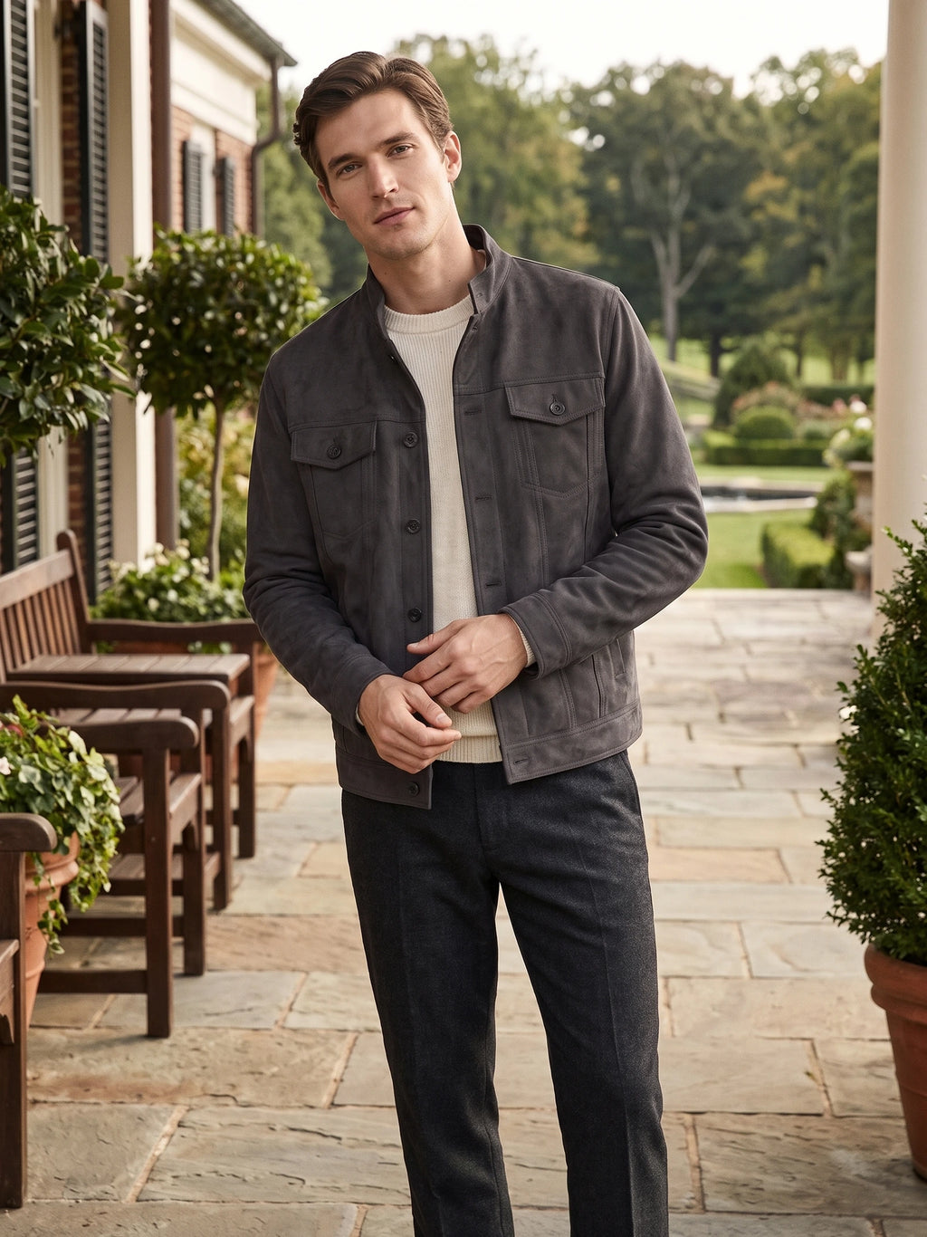 Model wearing a Gray suede fall jacket with a stand collar and buttoned flap pockets on a landscaped porch.
