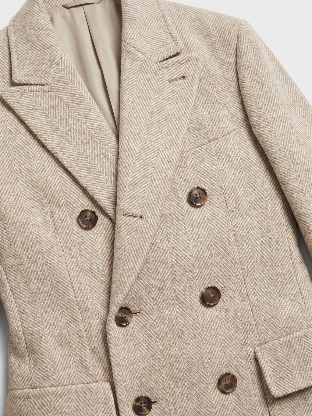 Close-up of a Beige wool Men Suit Coat with herringbone texture, peaked lapels, and double-breasted buttons.