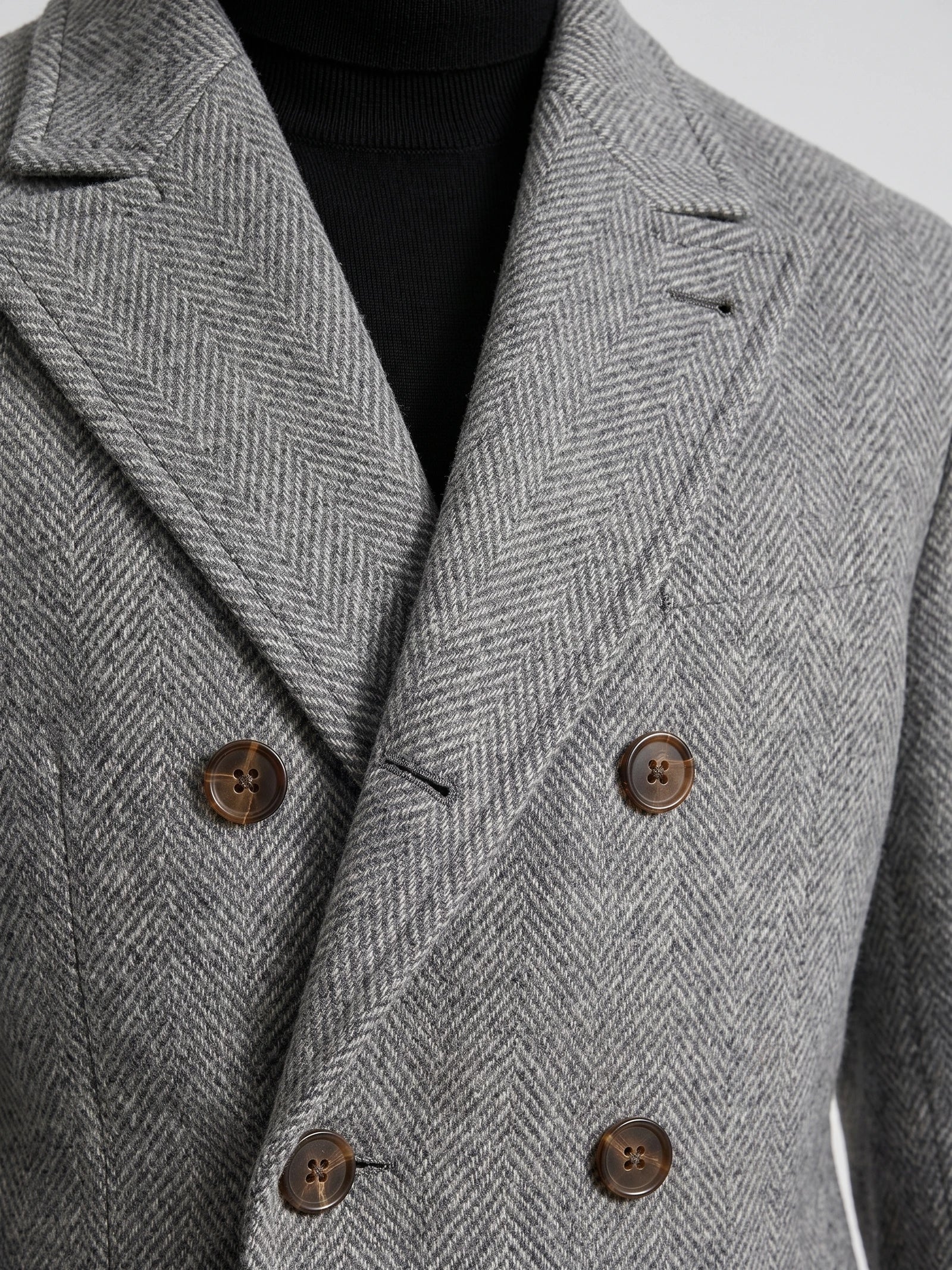 Close-up of a Gray Men Suit Coat with herringbone wool texture, notch lapels, chest welt pocket, and double-breasted buttons.