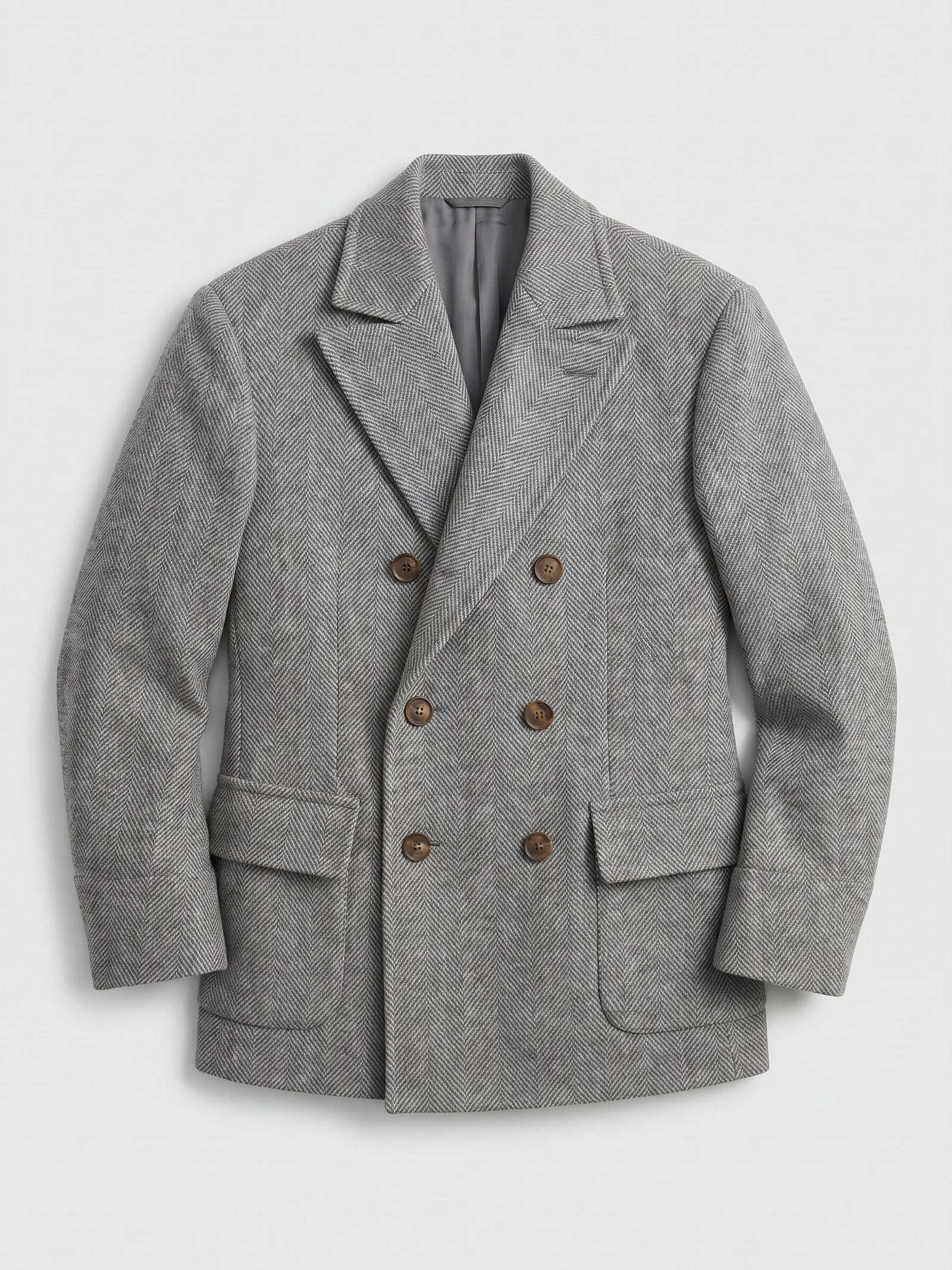 Gray wool men’s suit coat laid flat, featuring a herringbone weave, peak lapels, flap pockets, and six-button double-breasted front.