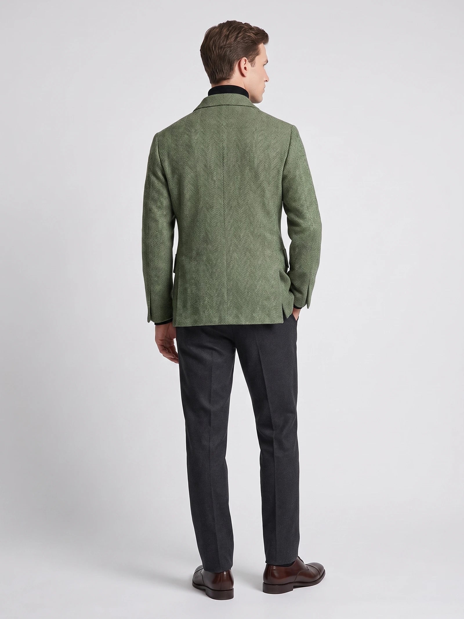 Rear studio view of a model wearing a Green wool Men Suit Coat with a herringbone pattern.