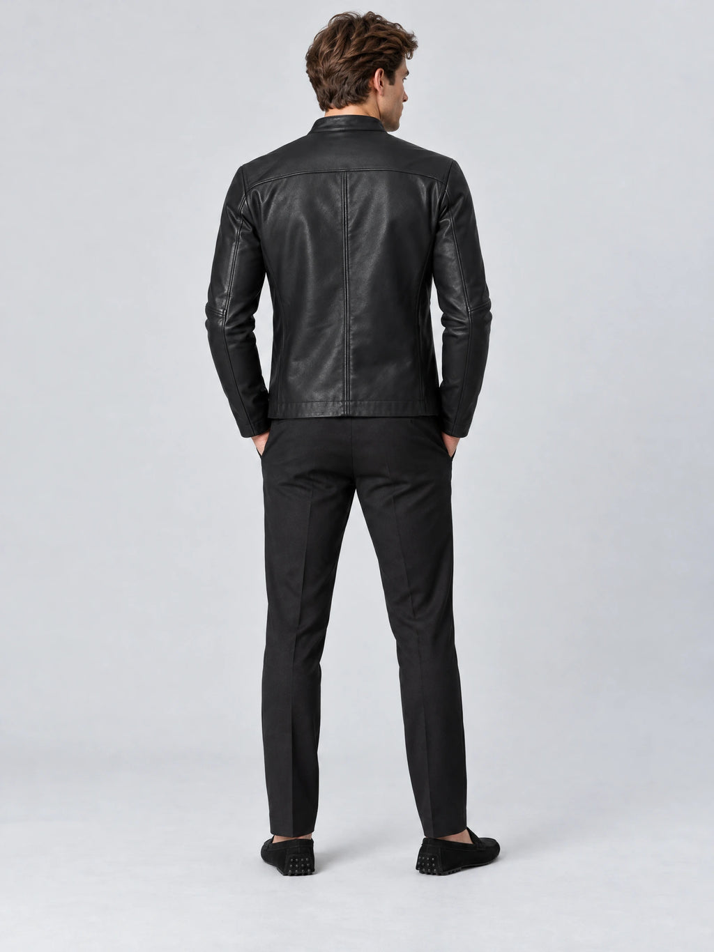 Rear view of a model wearing a Black tailored leather jacket with a fitted silhouette, shoulder yoke, and center back seam.