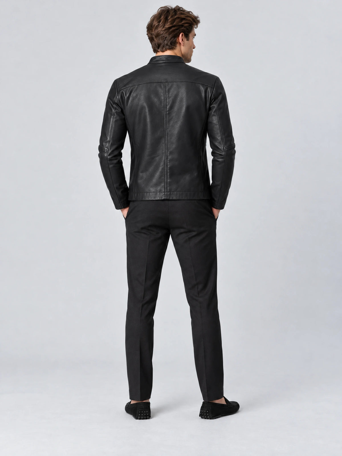 Rear view of a model wearing a Black tailored leather jacket with a fitted silhouette, shoulder yoke, and center back seam.