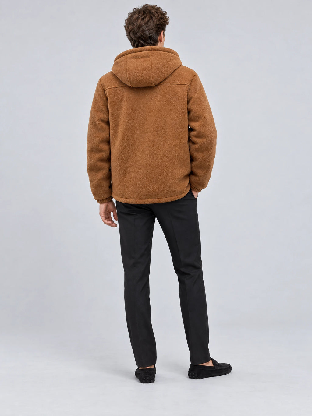 Rear studio view of a model wearing a Brown teddy jacket with a hood and textured finish.