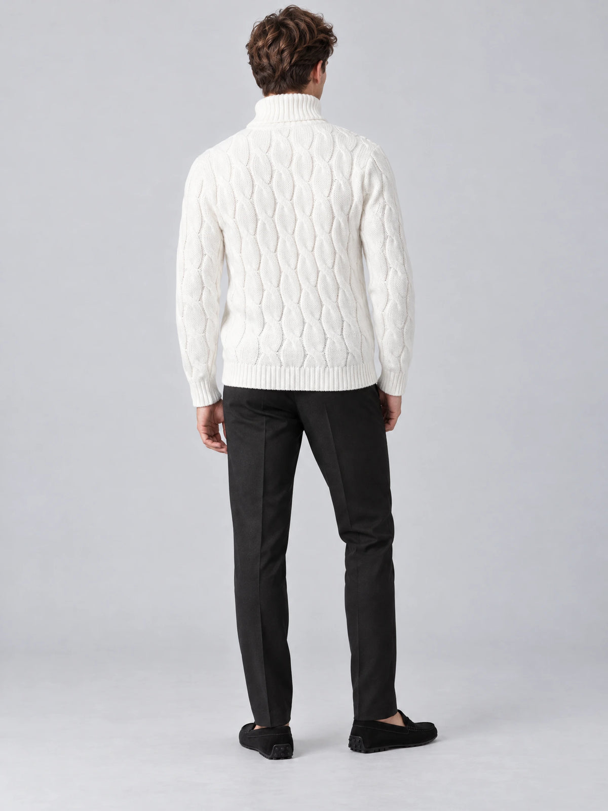 Rear studio view of a model wearing a White cotton Turtle Neck Sweater with cable-knit texture and ribbed collar, cuffs, and hem.
