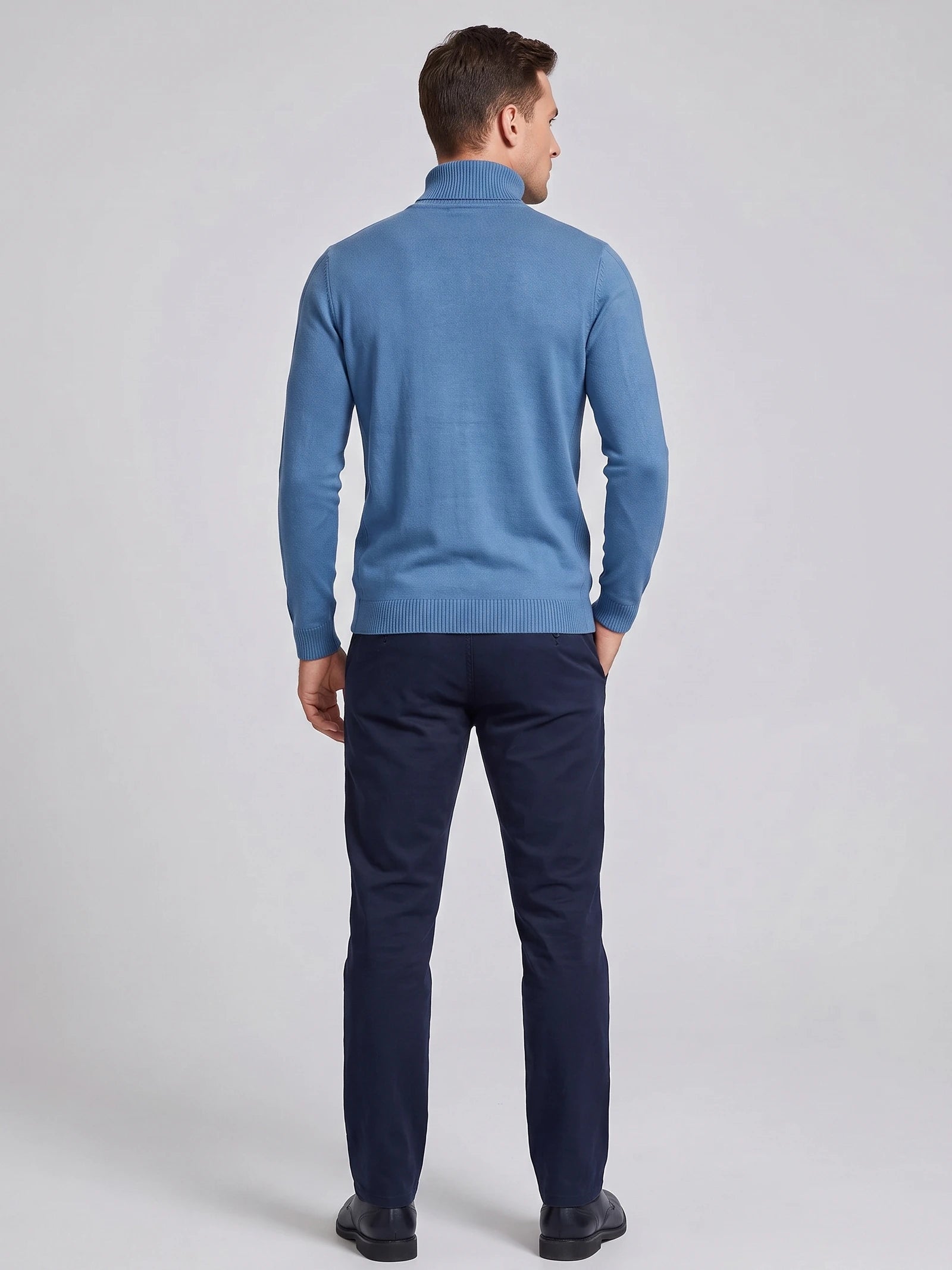 Rear studio view of a model wearing a Blue men's Turtleneck Sweater with a ribbed high neck, cuffs, and hem.