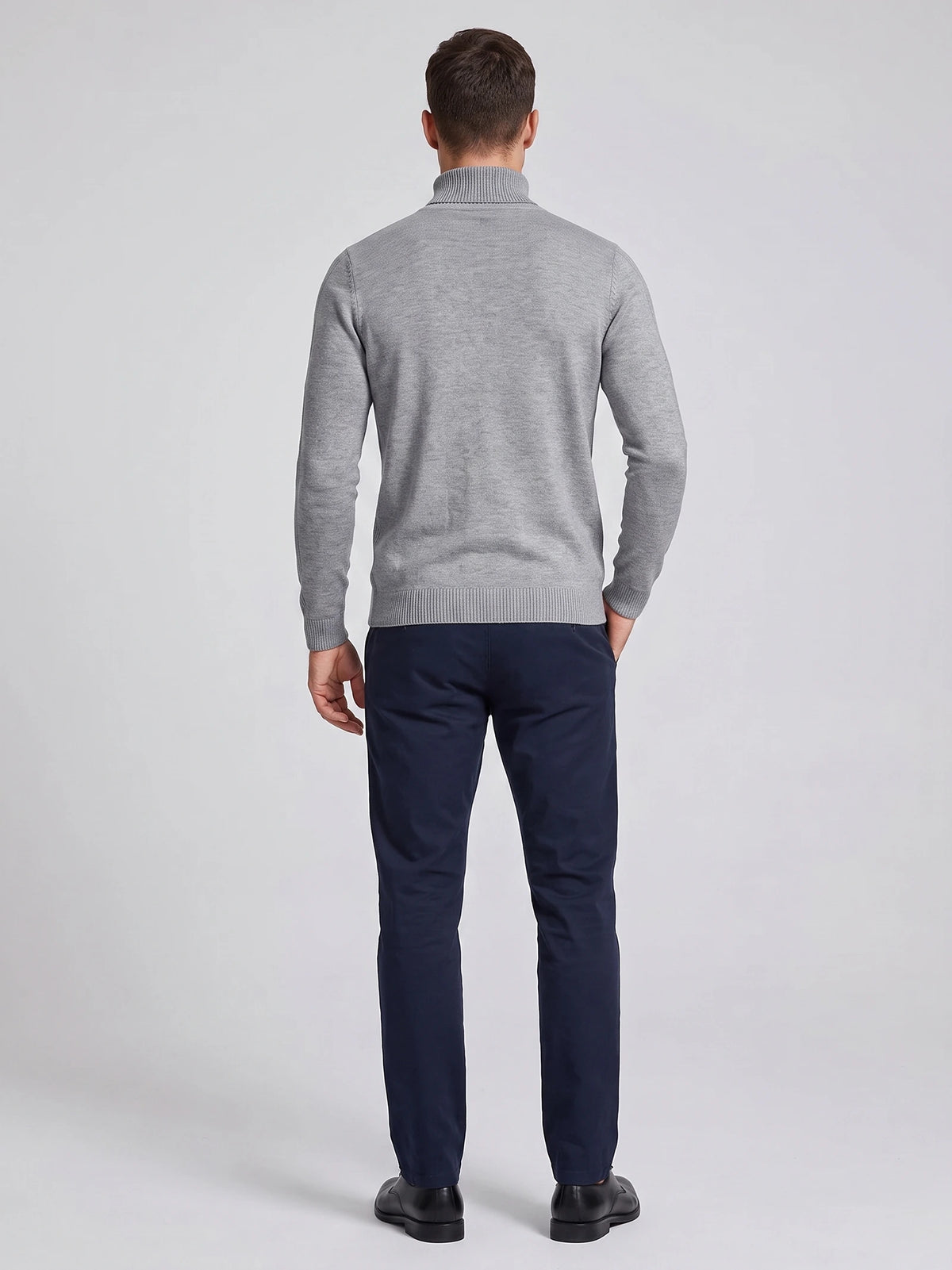 Rear studio view of a model wearing a Gray men's turtleneck sweater with long sleeves and ribbed cuffs and hem.