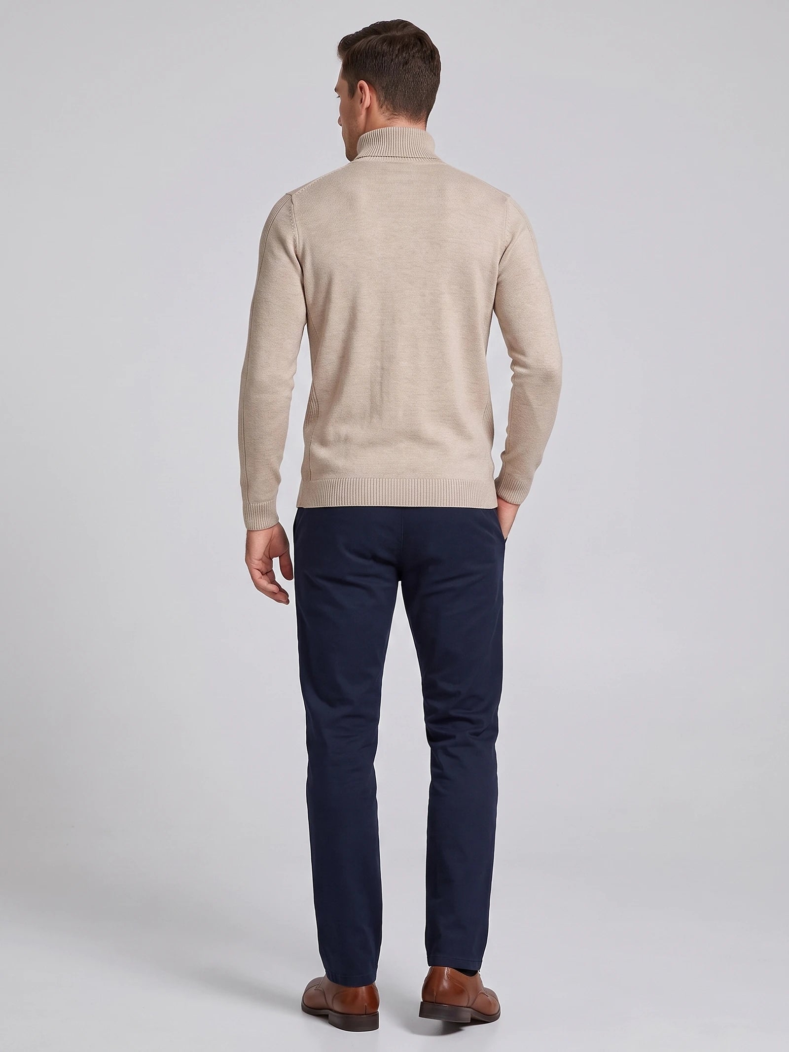 Rear studio view of a model wearing a Khaki men's Turtleneck Sweater with a ribbed high neck, cuffs, and hem.