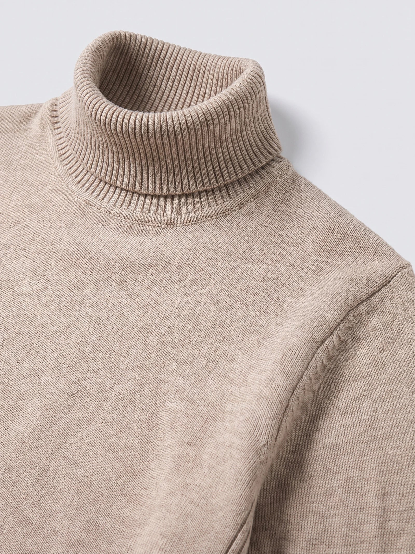 Close-up of the ribbed high neck and knit texture on a Khaki men's turtleneck sweater.