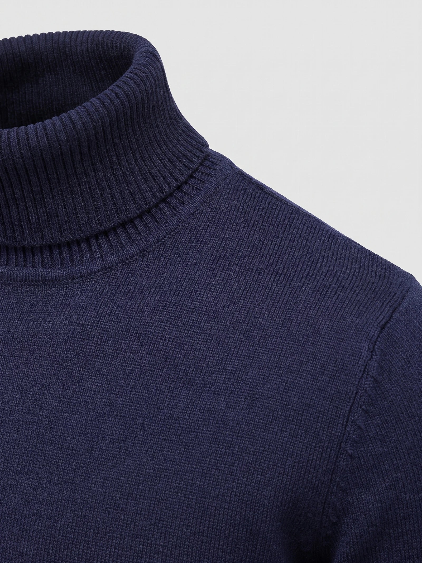 Close-up of the Navy Turtleneck Sweater showing its ribbed high neck, fine knit texture, and shoulder seam.