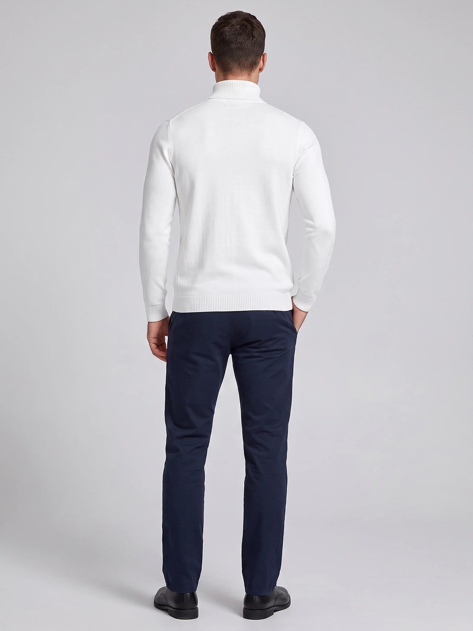 Rear studio view of a model wearing a White men's Turtleneck Sweater with ribbed collar, cuffs, and hem.
