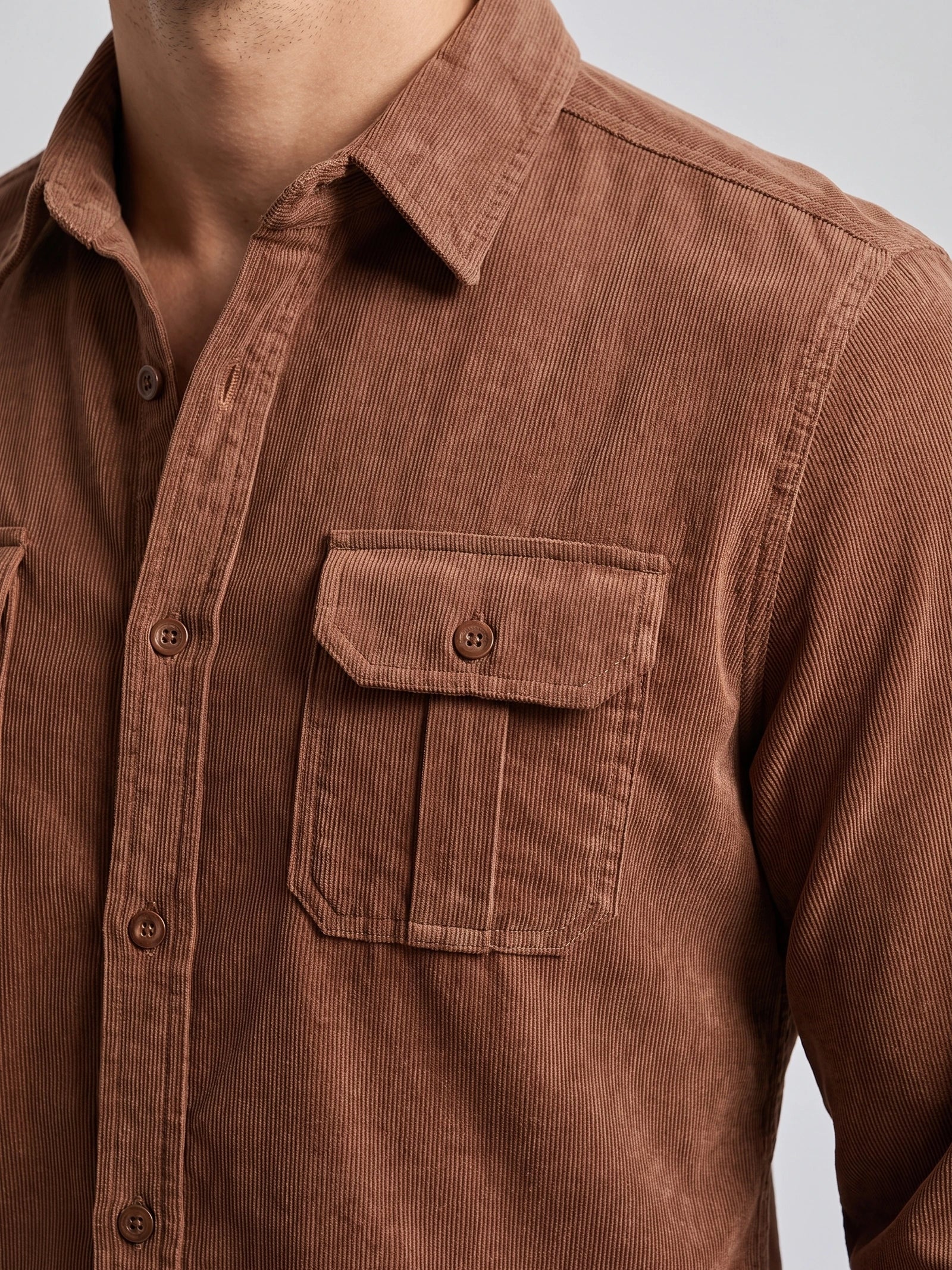 Close-up of a Brown men's Twill Tweed Shirt showing its ribbed cotton texture, pointed collar, button placket, and flap chest pocket.