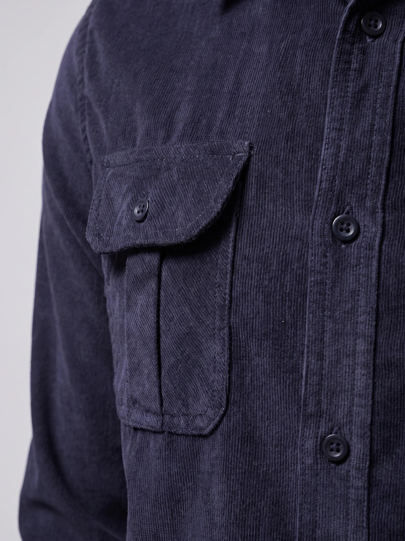 Close-up of the Navy Twill Tweed Shirt showing its ribbed cotton texture, button-front placket, and buttoned chest pocket.