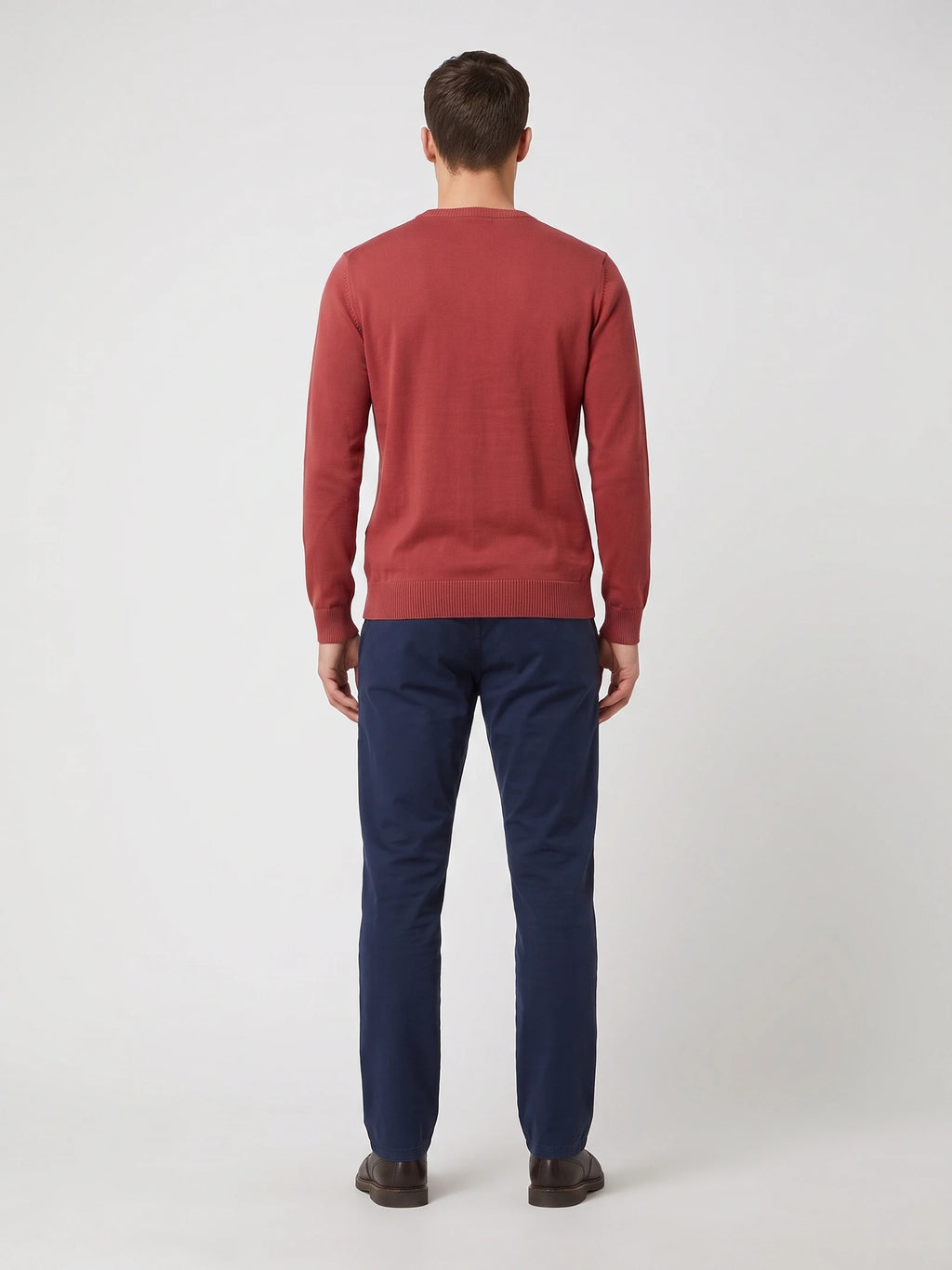 Rear studio view of a model wearing a Red cotton V-neck sweater with long sleeves and ribbed cuffs and hem.