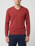 Front studio view of a model wearing a Red cotton V-neck sweater with long sleeves and ribbed trim.
