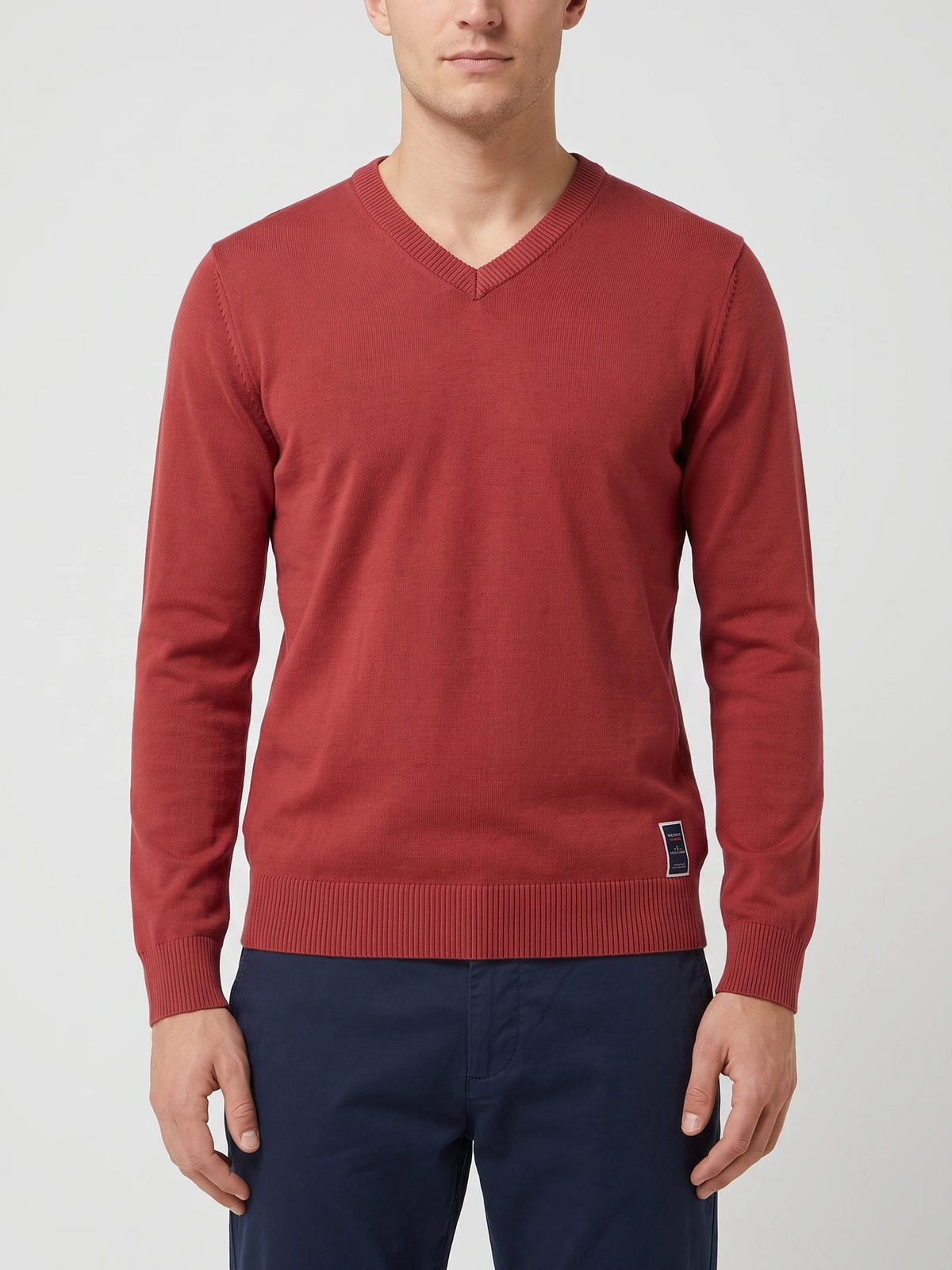 Front studio view of a model wearing a Red cotton V-neck sweater with long sleeves and ribbed trim.