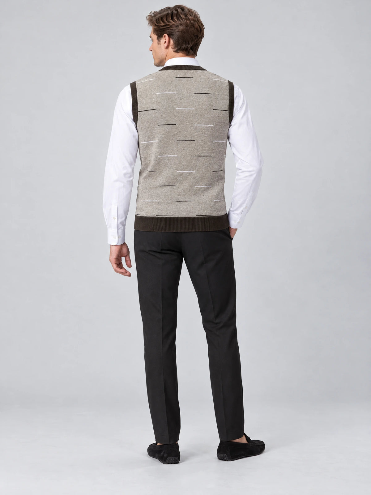 Rear studio view of a model wearing a Beige v neck sweater vest with a scattered dash pattern over a dress shirt.