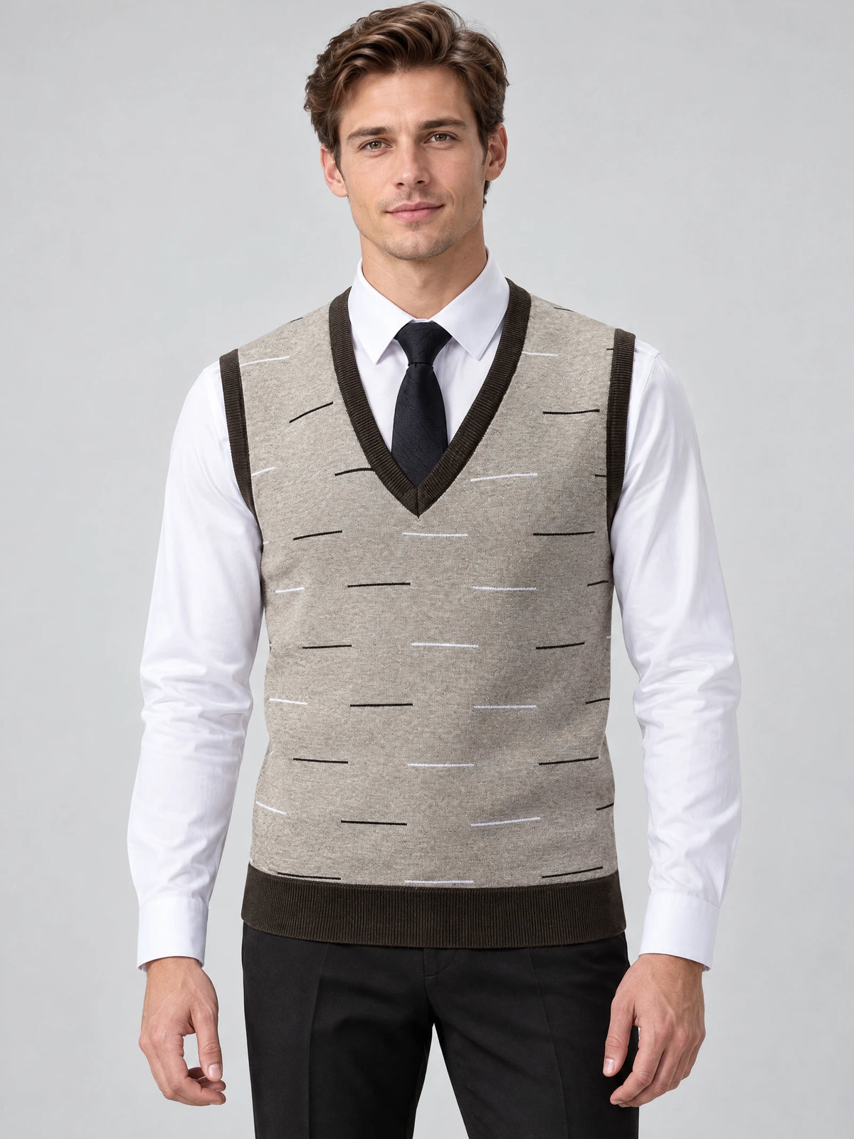 Front studio view of a model wearing a Beige v neck sweater vest with ribbed trim and a subtle linear pattern over a dress shirt and tie.