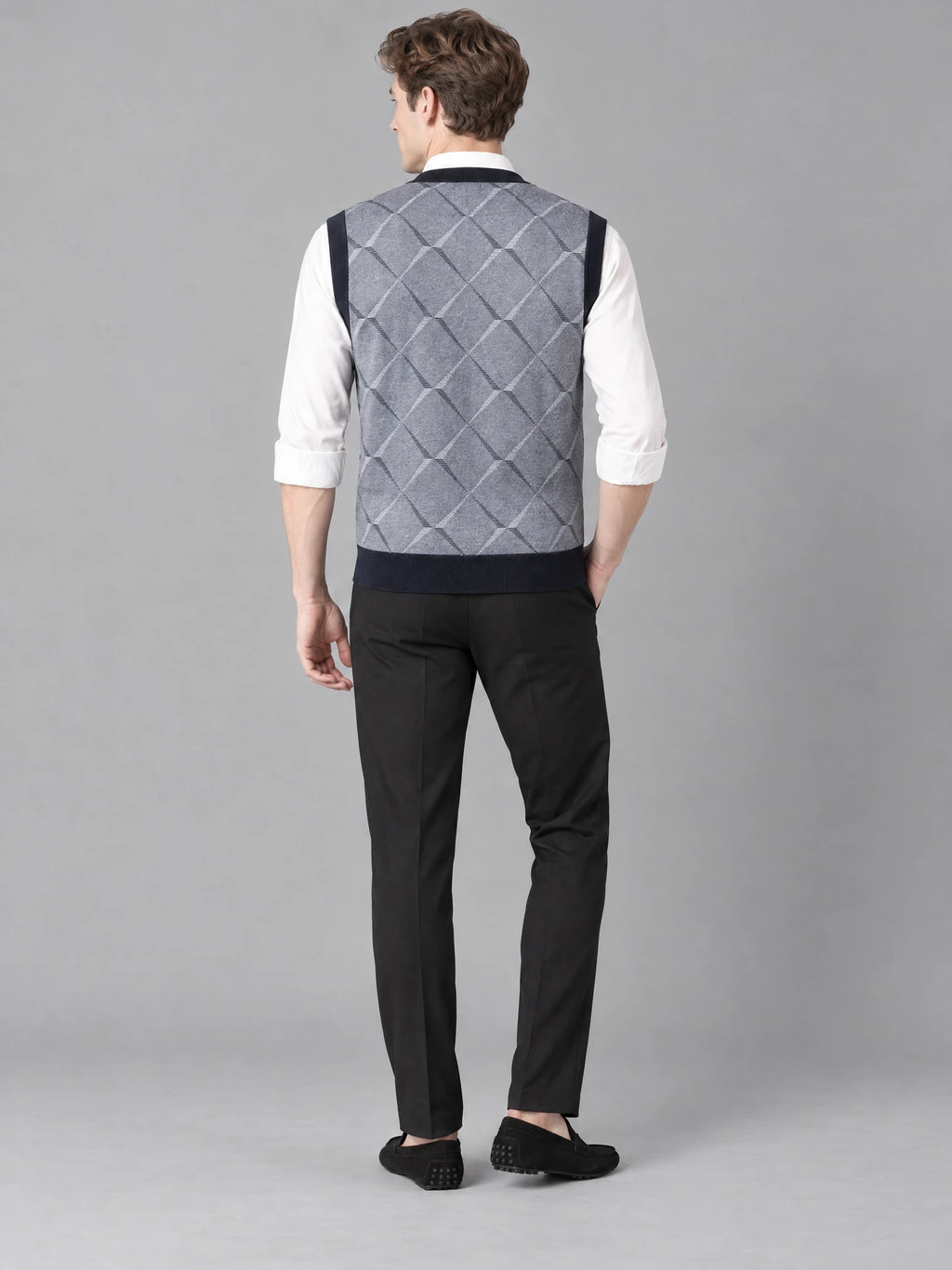 Rear studio view of a model wearing a Gray v neck sweater vest with a diamond-knit back pattern.