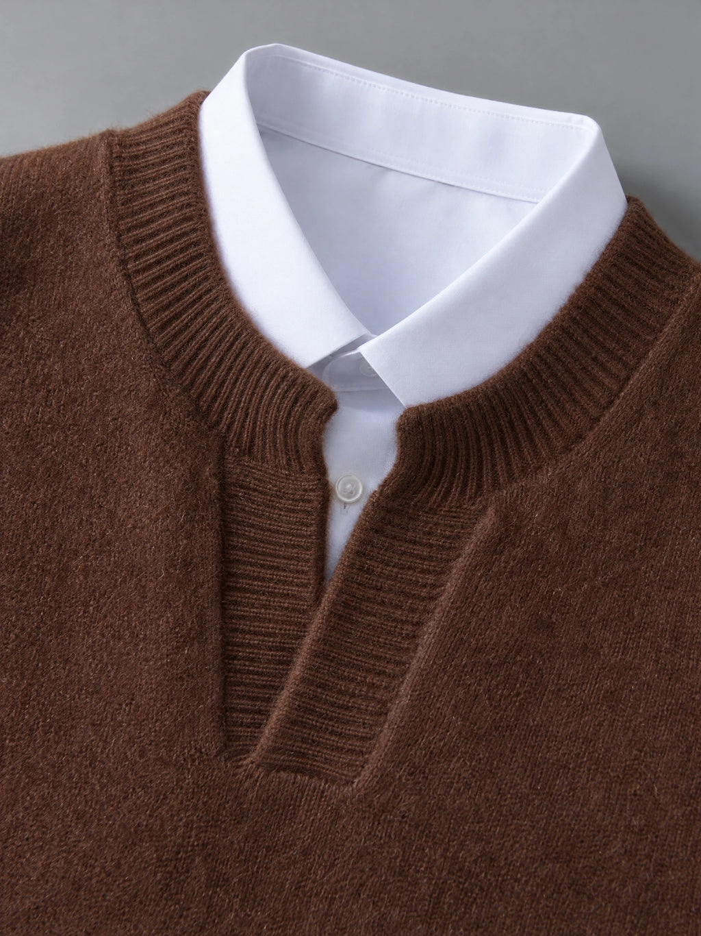 Close-up of the Brown wool v neck sweater vest with ribbed neckline layered over a collared shirt.