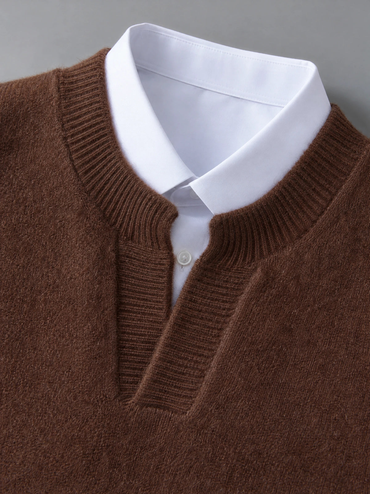 Close-up of the Brown wool v neck sweater vest with ribbed neckline layered over a collared shirt.