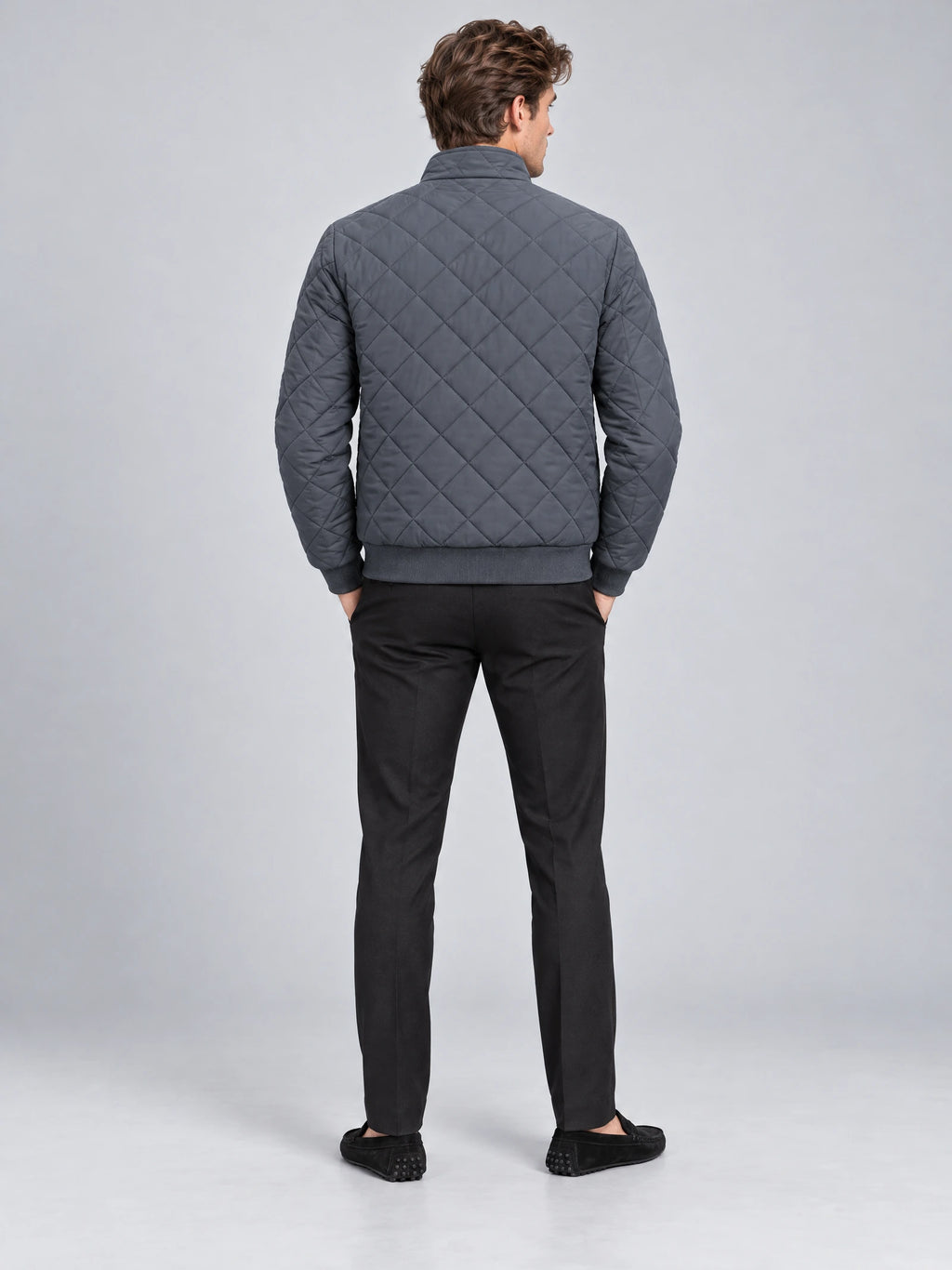 Rear view of a model wearing a Gray Winter Bomber Jacket with diamond quilting, ribbed hem, and cuffs.